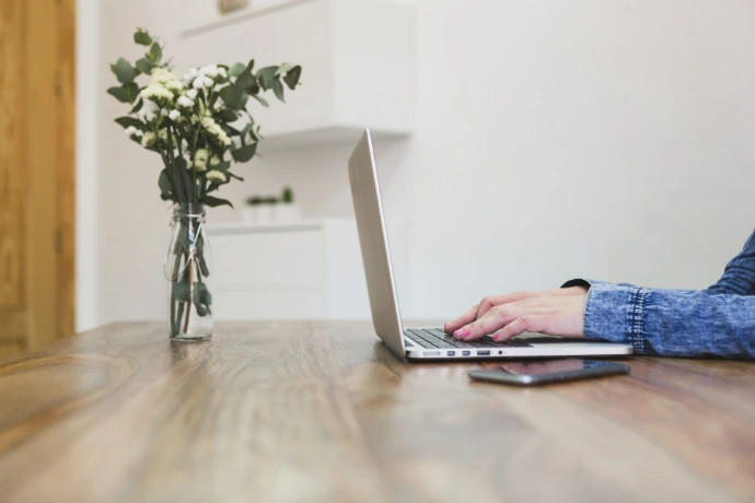 Persona escribiendo en una computadora portátil sobre una mesa de madera