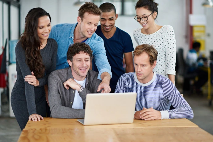 Grupo de profesionales trabajando juntos frente a una computadora portátil durante un taller